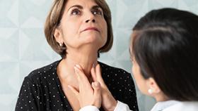 A doctor checking a lady's thyroid
